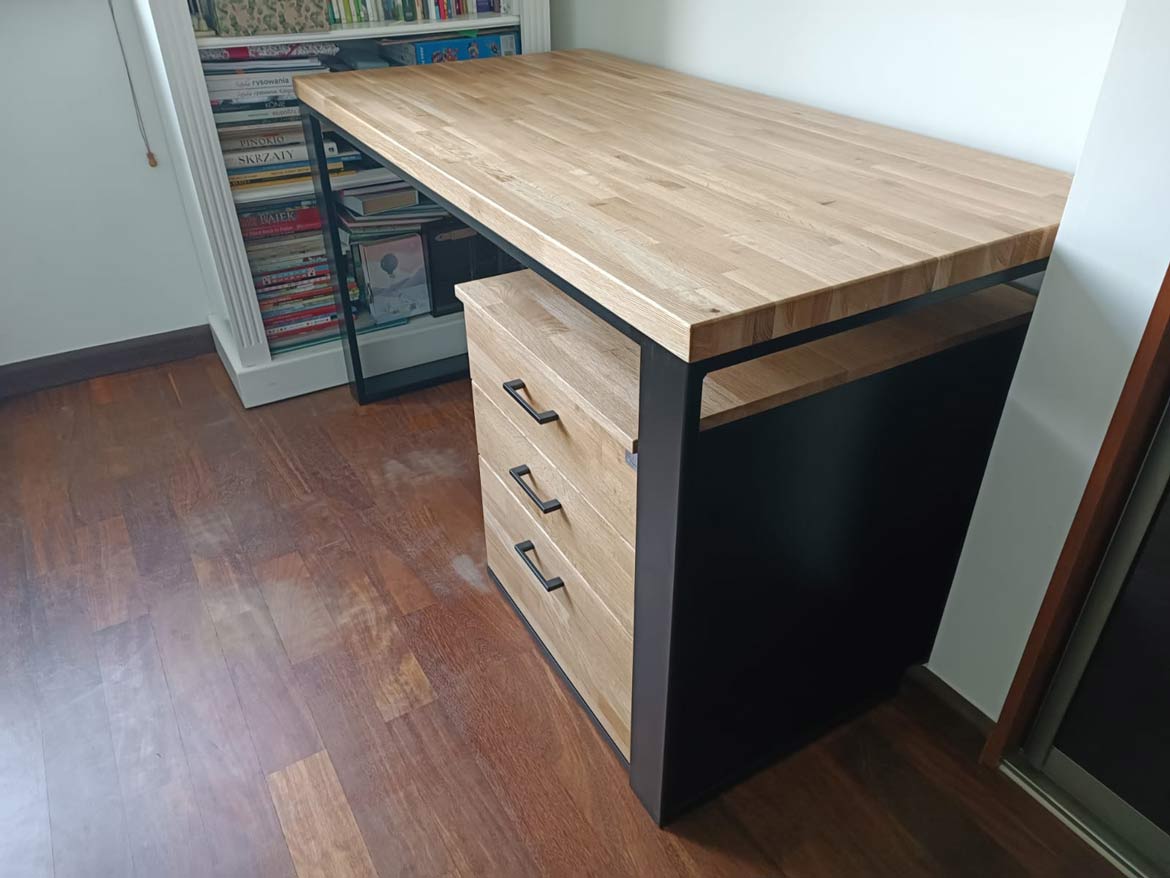 Desk with oak top and black metal legs, under the desk on the right side of the wooden pedestal with three shulada black handles