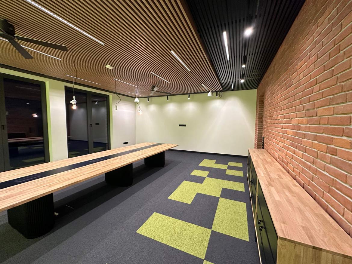 Industrialny stół konferencyjny w jasnej sali z przeszkloną ścianą i oświetleniem punktowym