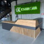 Modern reception counter with wooden top and geometric front in industrial interior
