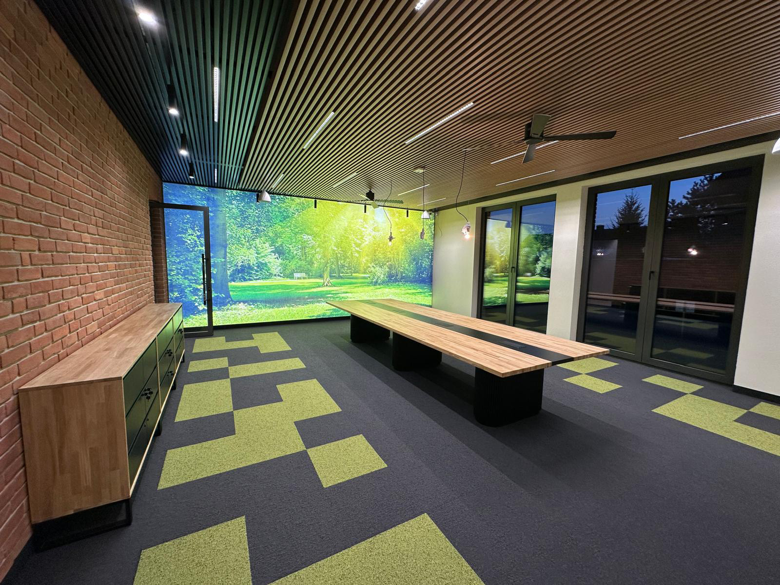 Designerski stół konferencyjny w sali spotkań z sufitem z lameli i geometryczną podłogą