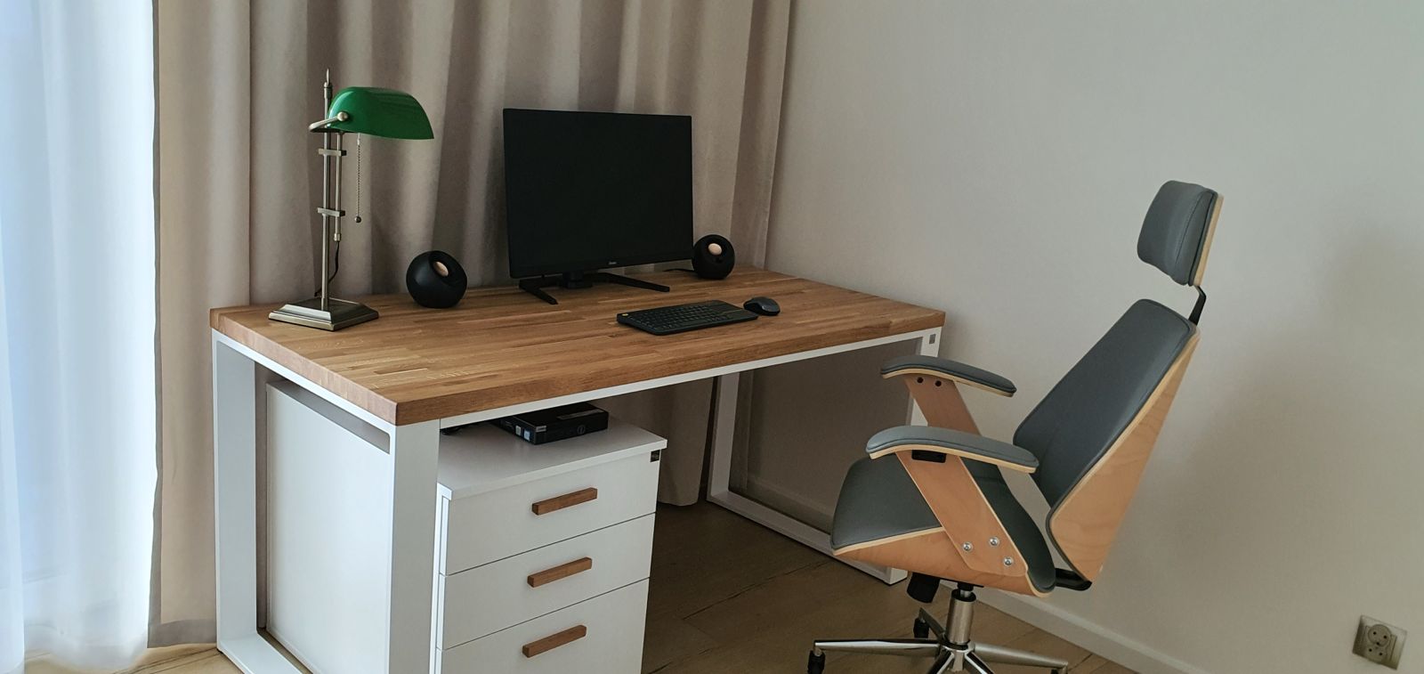 Białe biurko z zieloną lampką na blacie