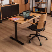 A height-adjustable home office desk in a modern interior featuring wood and black accents