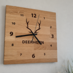 A wooden wall clock made of natural oak as a decoration for a light-colored wall in the living room