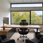 An office with a wooden desk and black cabinetry next to a large window