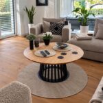 A round oak coffee table for a living room with light-colored furniture and hardwood floors