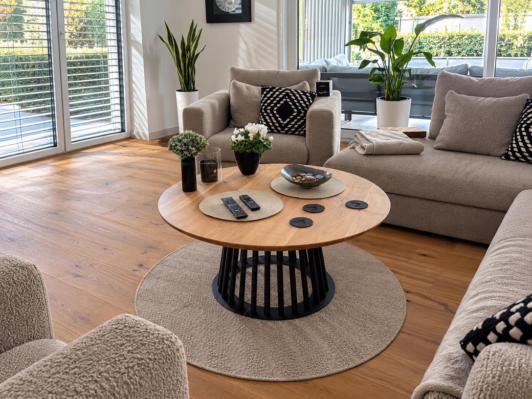 A round oak coffee table for a living room with light-colored furniture and hardwood floors
